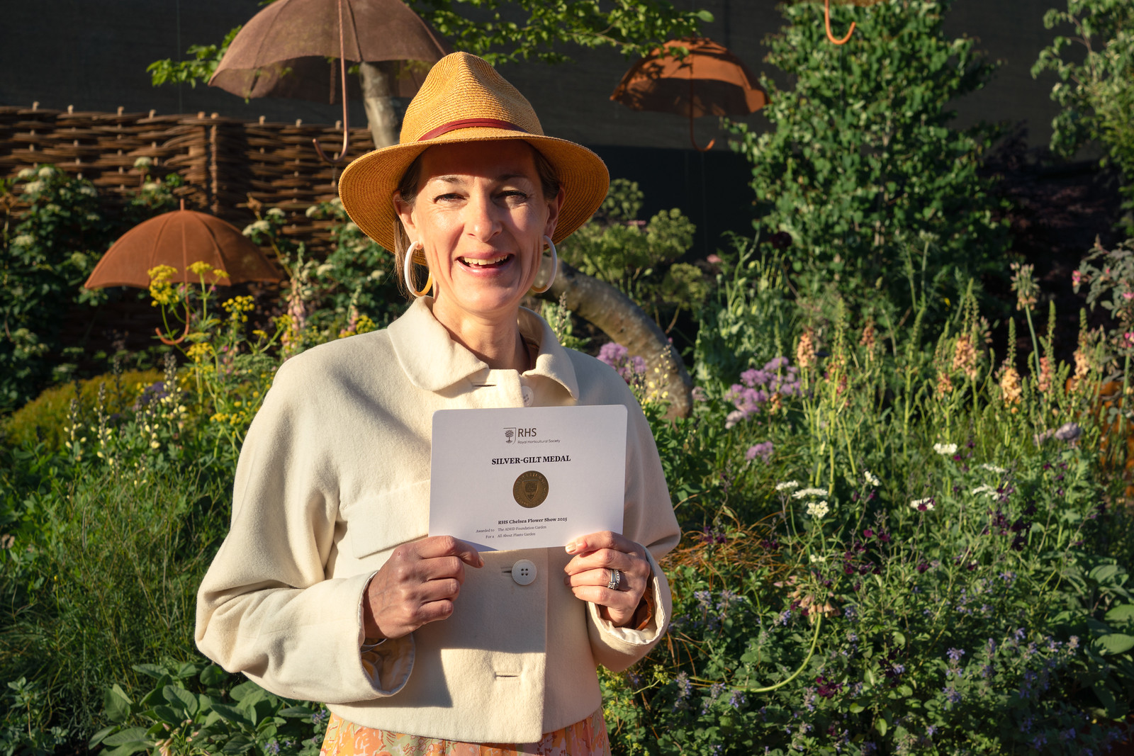 Katy Terry, ADHD Foundation Garden Designer, smiling and holding up the Silver-Gilt Medal Certificate