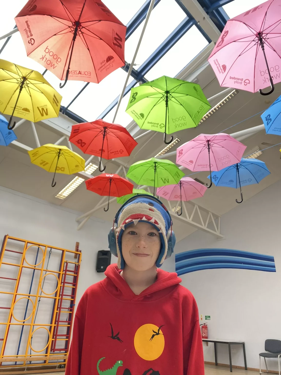 George stands in his classroom with an Umbrella Project installation above him