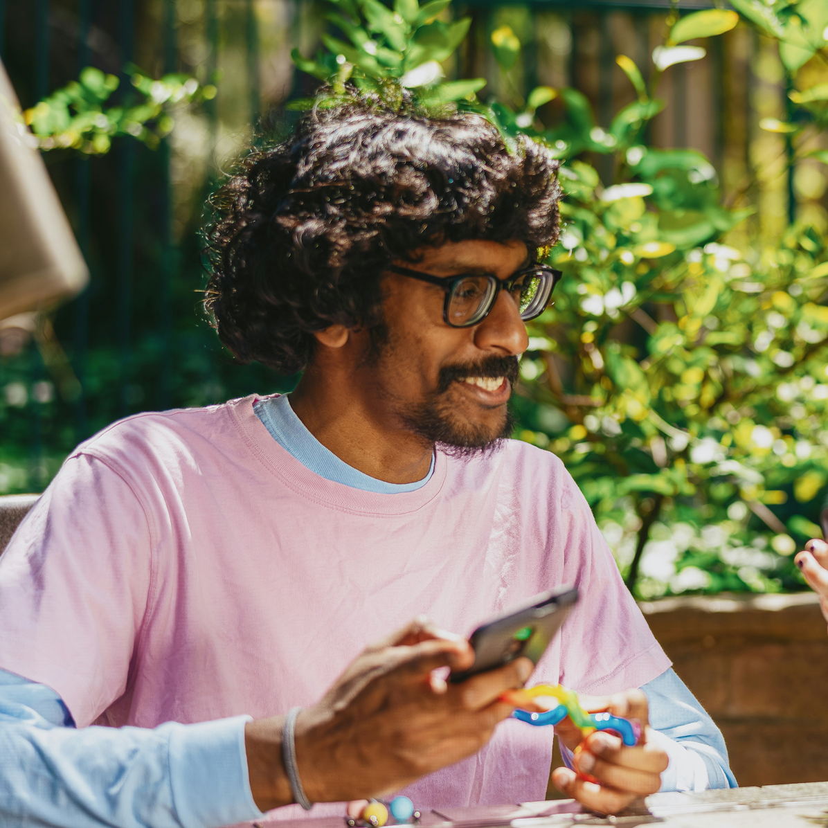 A young man sat down laughing and smiling whilst looking at something funny on their phone