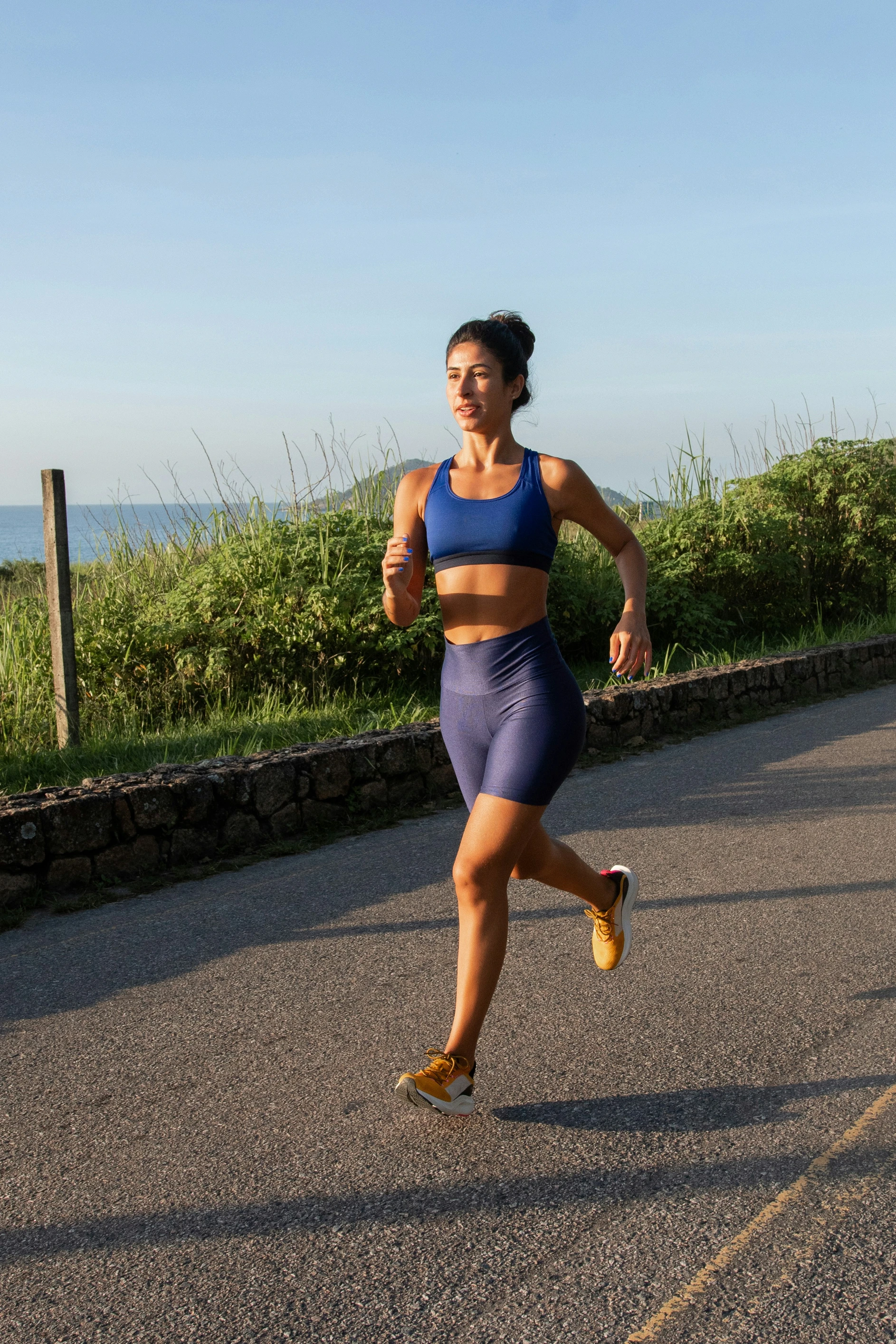 A woman running down a road on a sunny day