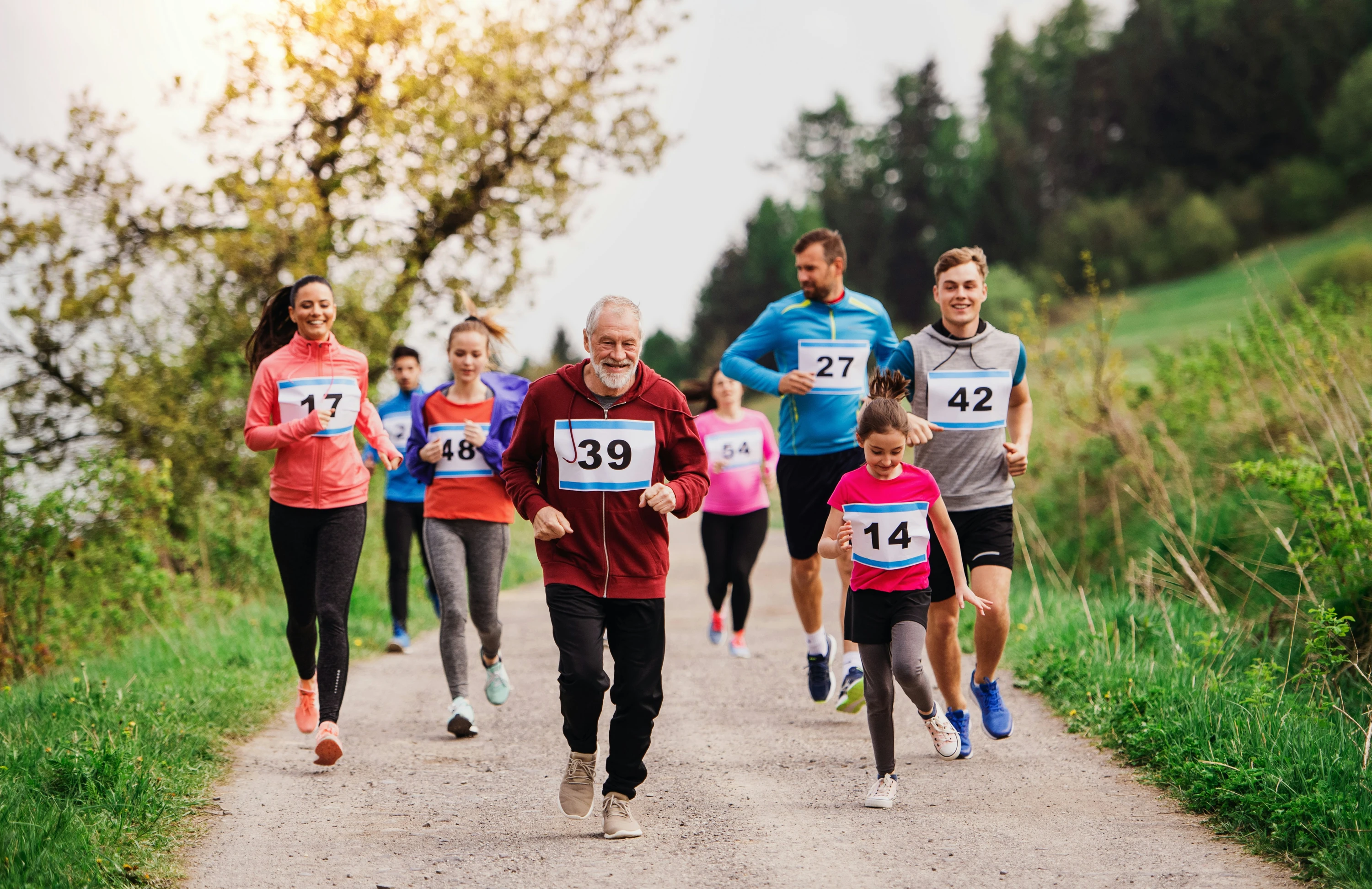 A large group of active multi generation people running a race competition in nature