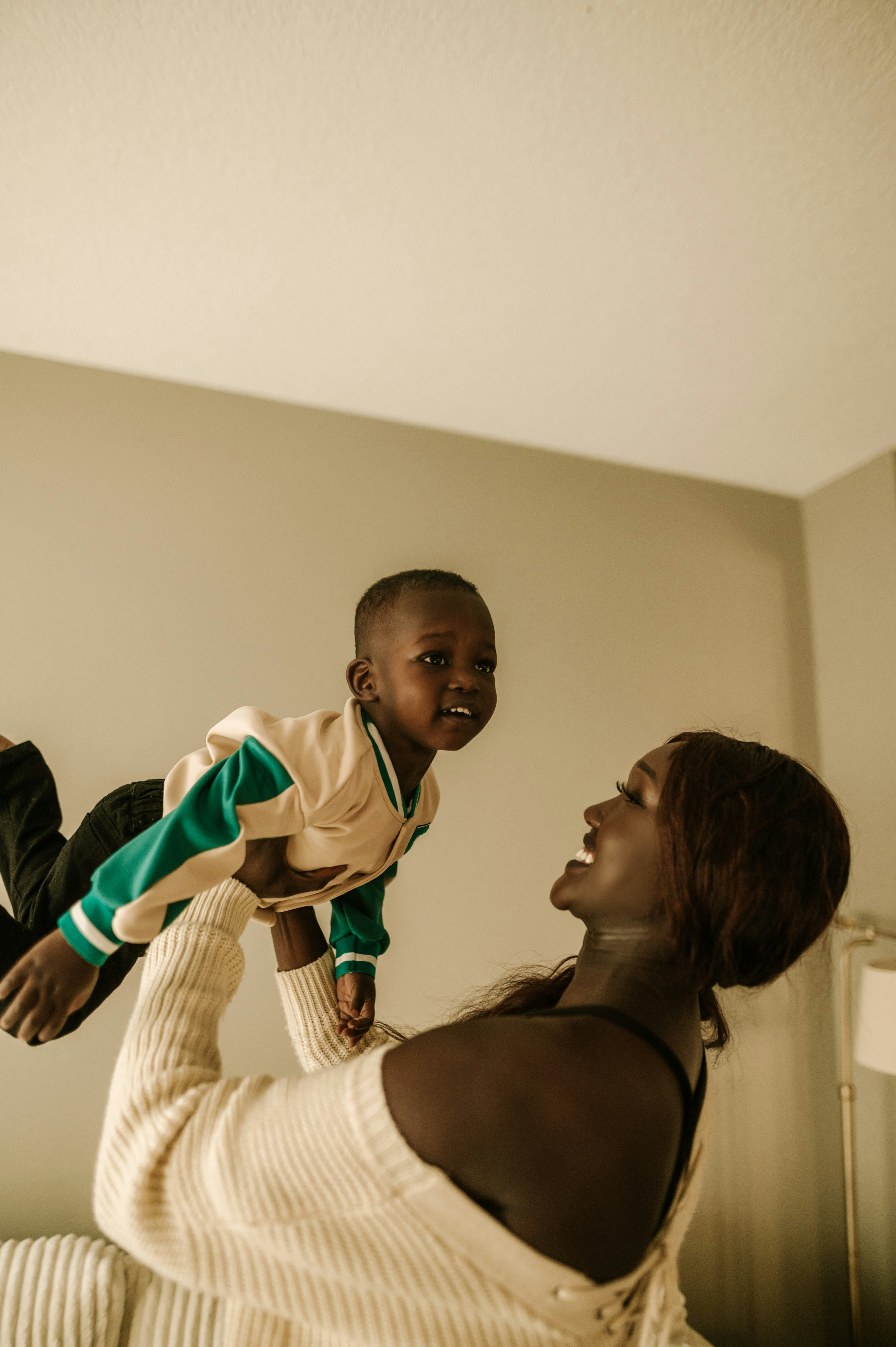 A woman holds a child up in the air as they both smile