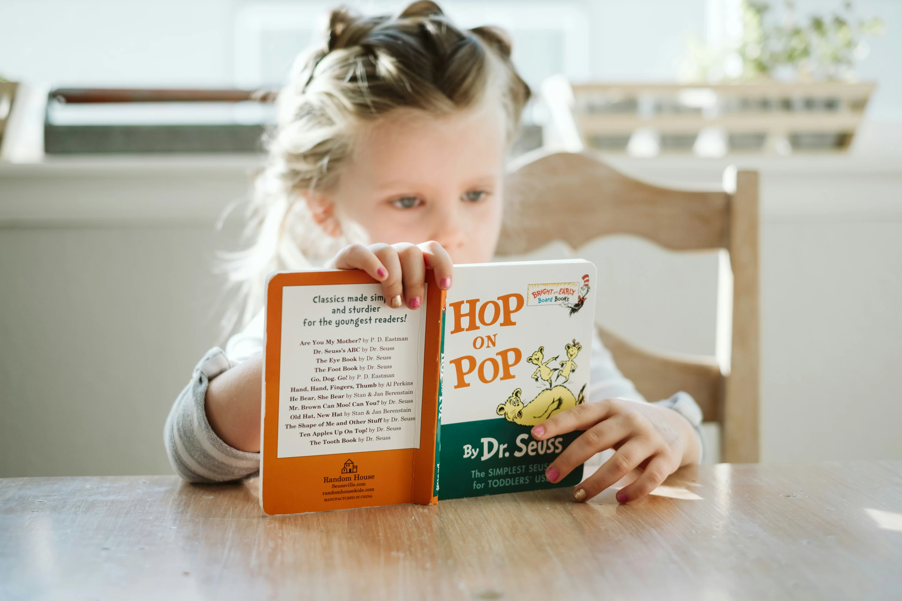 A young girl sitting at a table while reading a book