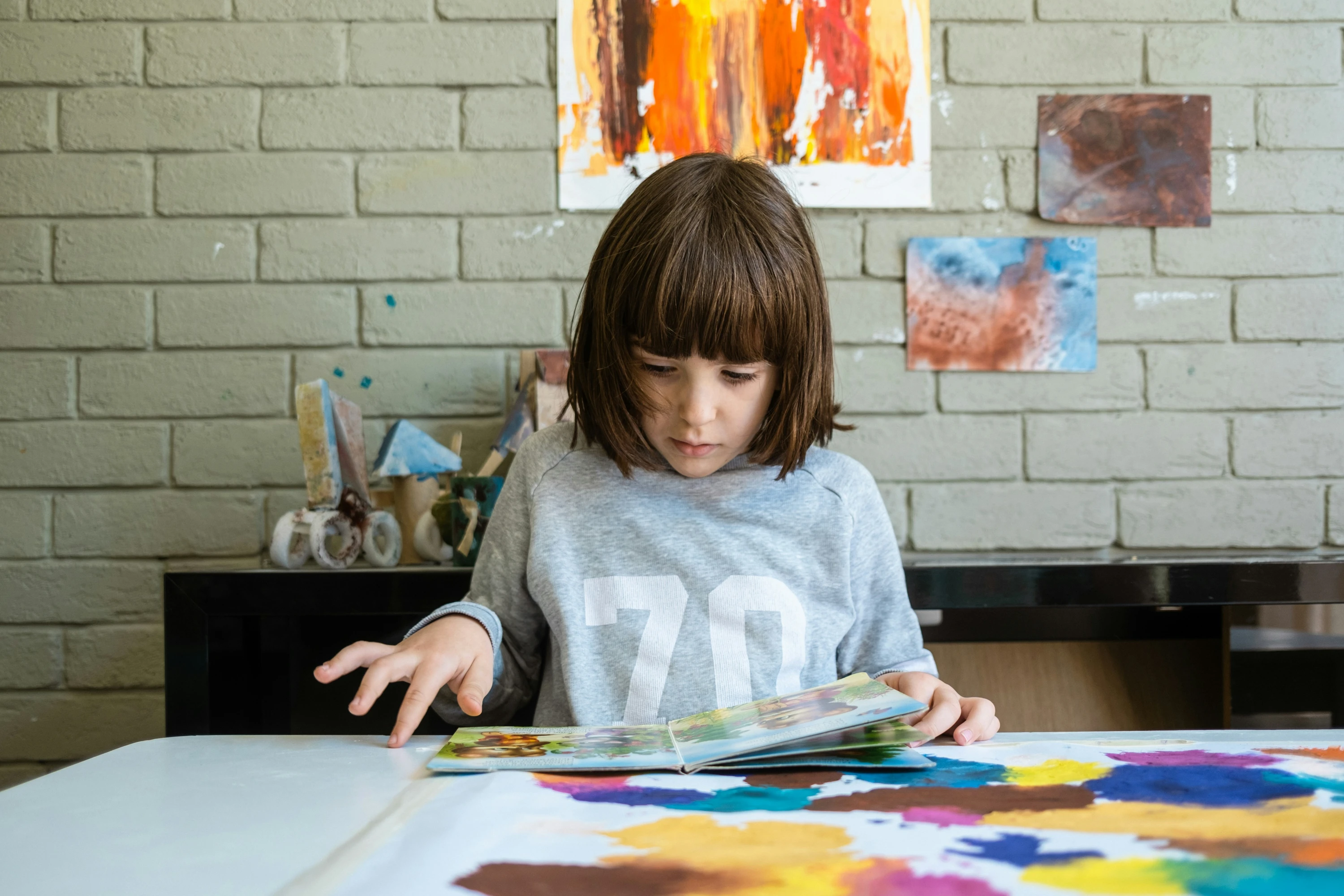 A young girl sitting at a table looking through a comic