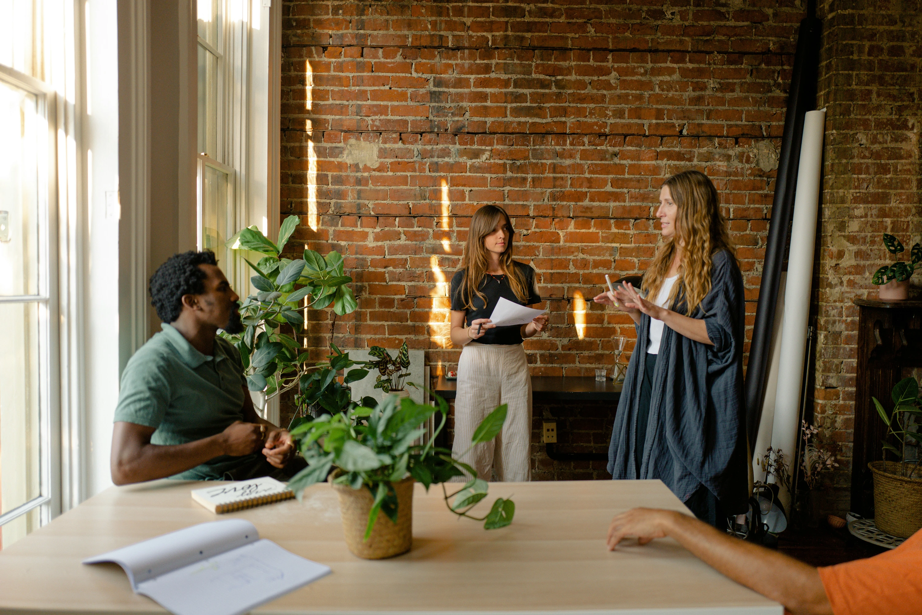 A group of people are stood presenting to others in a softly lit office