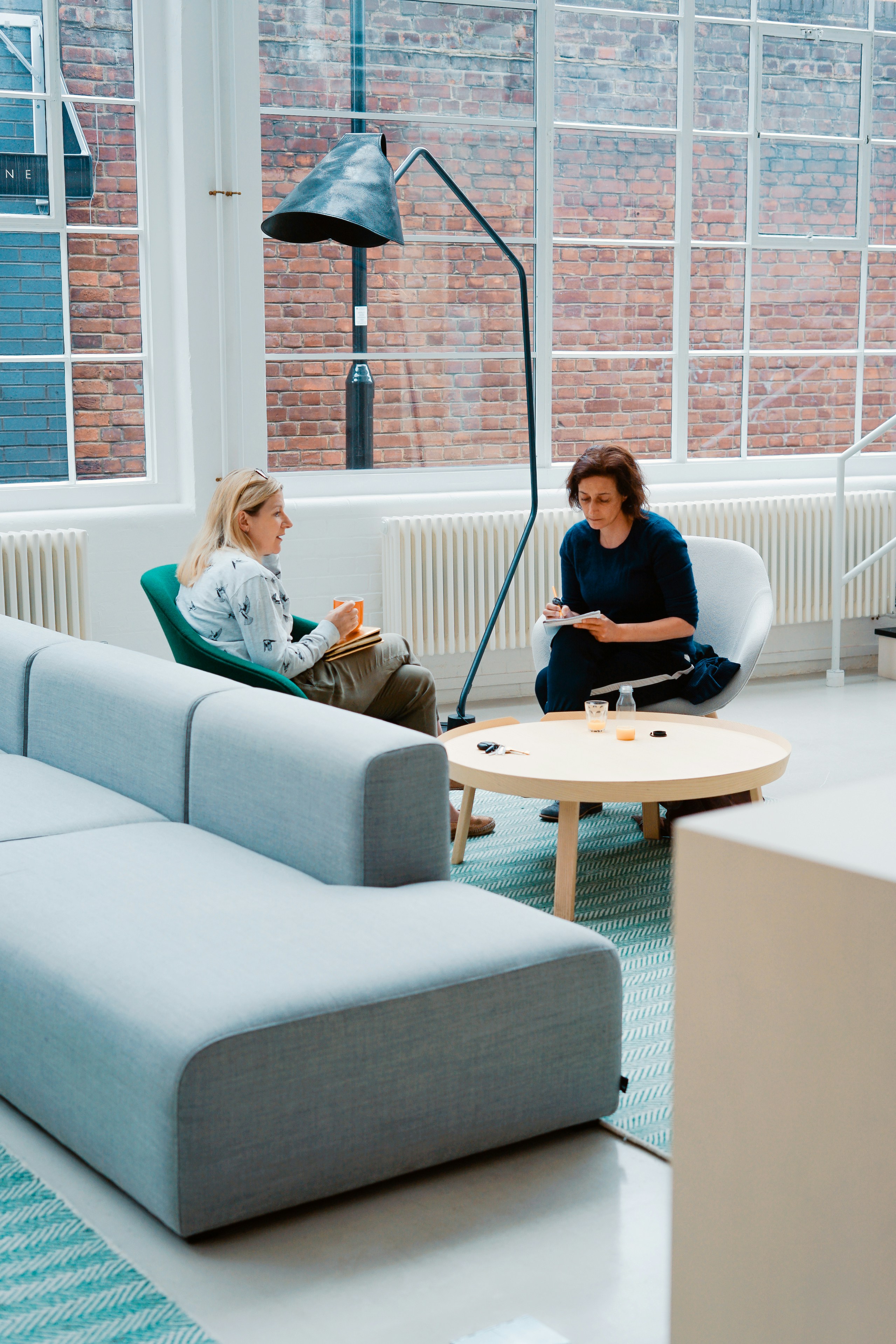 Two women sit down in a professional setting with paperwork in their hands